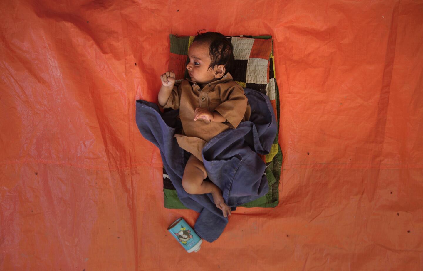 Three-month-old infant lies on a piece of tarp at a camp for flood victims in the Badin district of Pakistan.