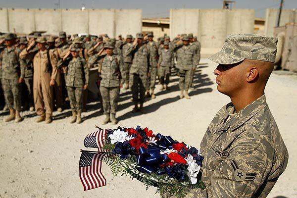 U.S. Airman 1st Class Sean J. Vazquez, 20, of Fitchburg, Mass., holds a wreath dedicated to those who have died in the Afghanistan war during a ceremony at Kandahar airfield, where thousands of American troops are stationed. In the background, members of the Air Force's 451st Expeditionary Wing stand at attention.
