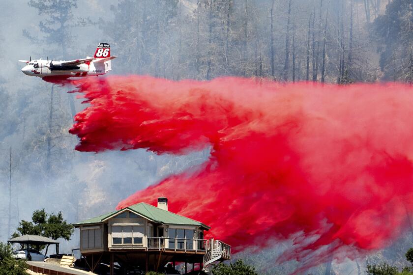 An air tanker drops retardant behind a home while battling the Toll Fire near Calistoga, Calif., on Tuesday, July 2, 2024. An extended heatwave blanketing Northern California has resulted in red flag fire warnings and power shutoffs. (AP Photo/Noah Berger)