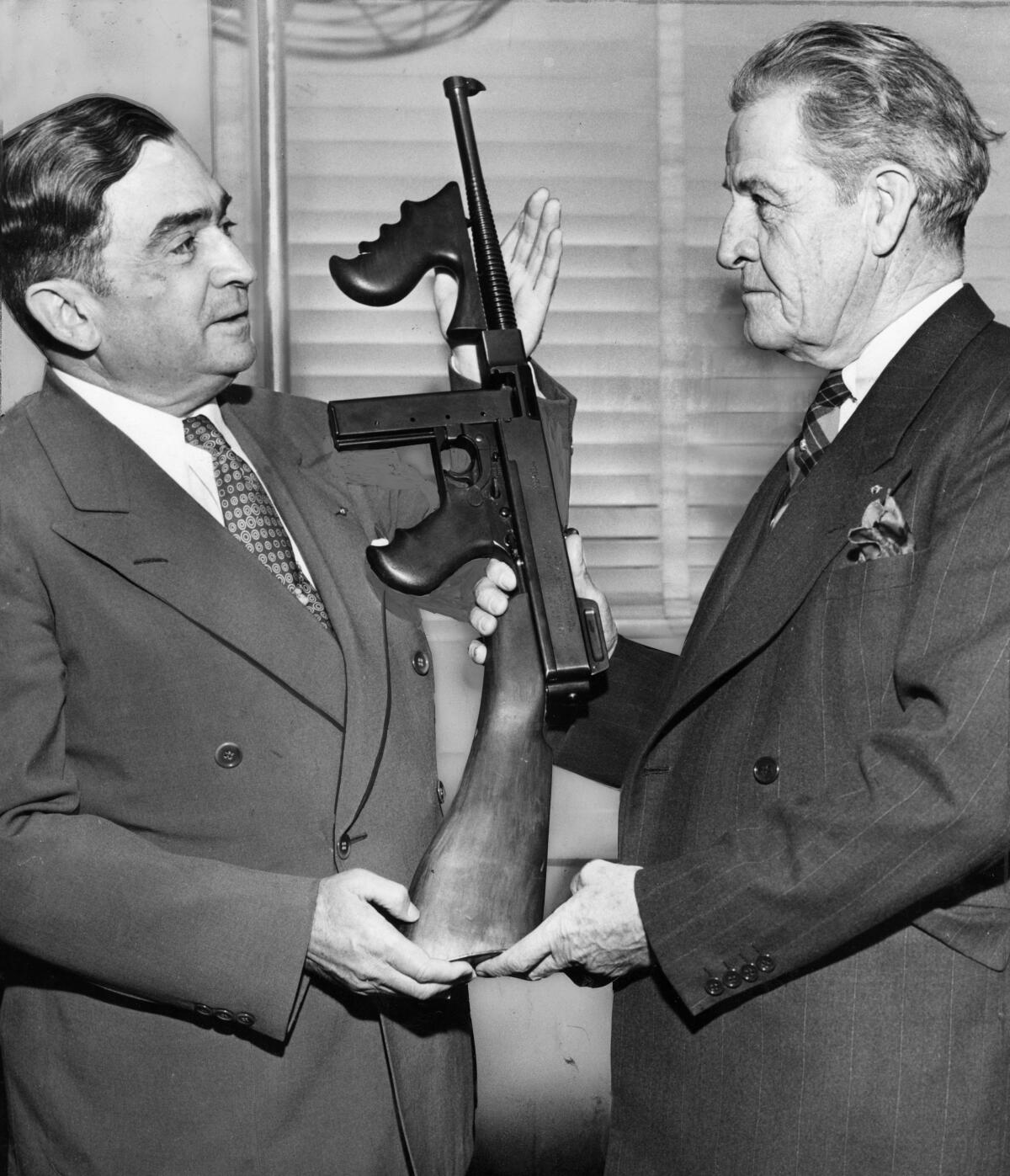 Sheriff Eugene Biscailuz, left, receives a machine gun for his collection 
