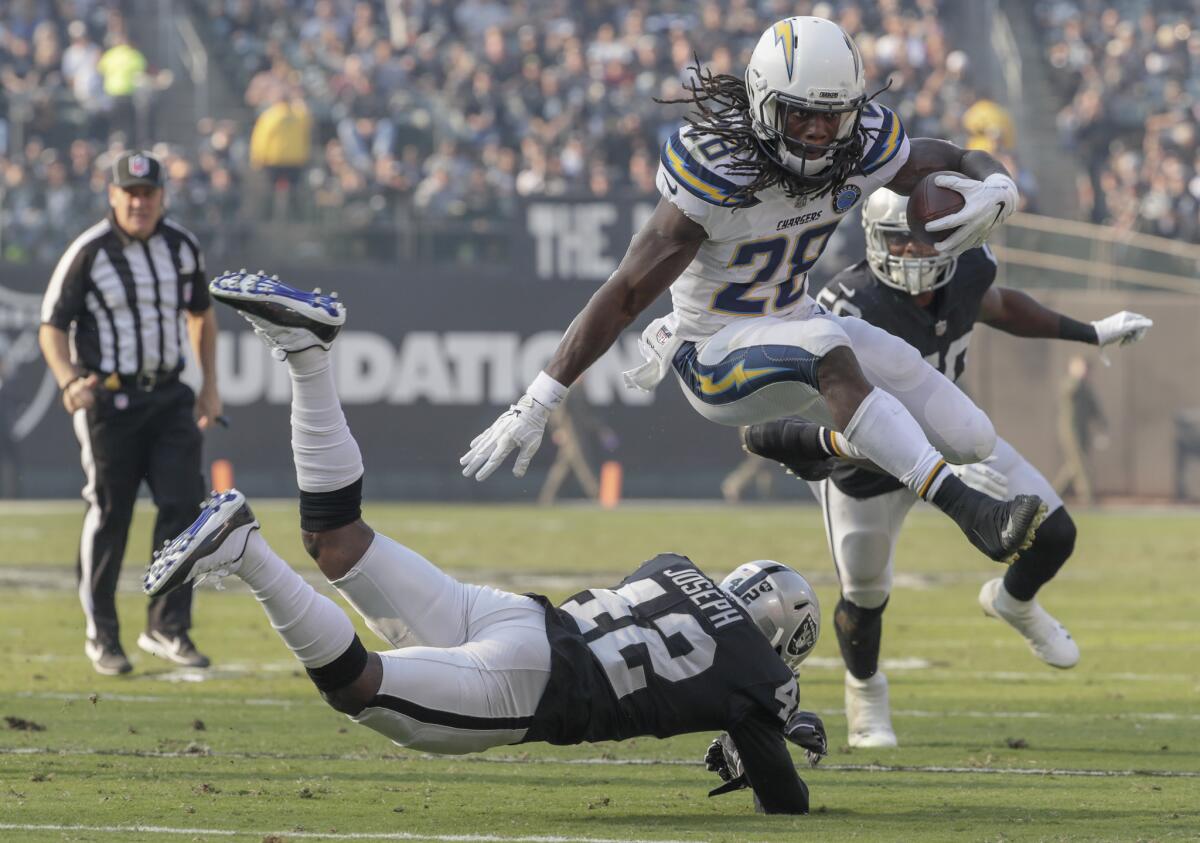Chargers running back Melvin Gordon hurdles over Oakland Raiders safety Karl Joseph during a second-half drive at Oakland-Alameda County Coliseum on Sunday. Gordon rushed 18 times for 93 yards, caught five passes and 72 yards and scored a touchdown.