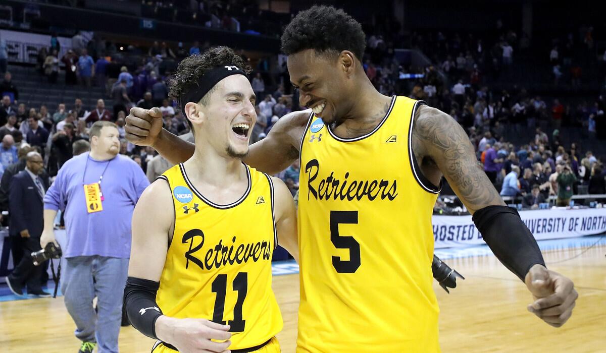 Maryland Baltimore County's K.J. Maura (11) and Jourdan Grant (5) celebrate their 74-54 victory over Virginia on March 16.