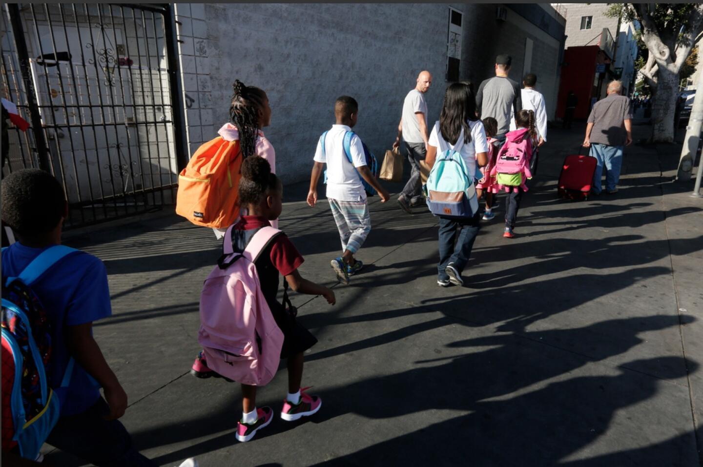 Ryan Locante, technology administrator for School on Wheels, walks with the students on skid row, two by two, on San Pedro Street. Center workers have the students yell, “Kids coming through! Kids, kids coming through!”