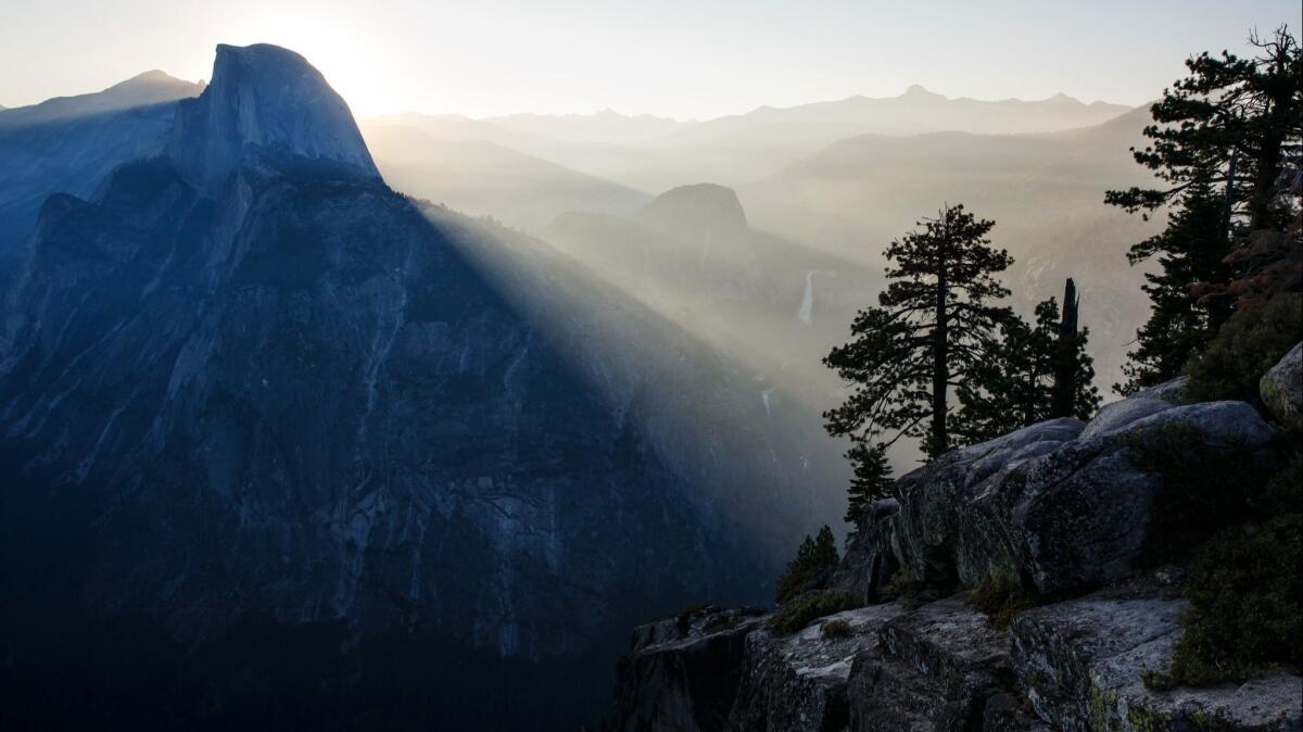 Visitors watch the sun rise behind Half-Dome, in Yosemite National Park, Calif.