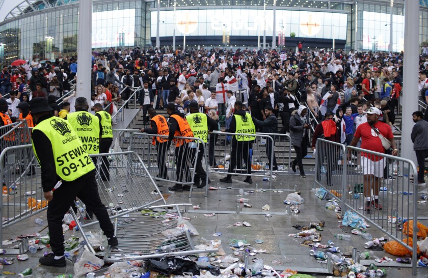 FILE - Stewards replace barricades after they were knocked over by supporters outside Wembley Stadium in London, during the Euro 2020 soccer championship final match between England and Italy, on July 11, 2021. An investigation into the disorder at the European Championship final says aggression by England fans exposed an “embarrassing” part of the national culture that endangered lives and should lead to entry to stadiums being prohibited to anyone chanting abuse and high on drugs or drunk. (AP Photo/David Cliff, File)