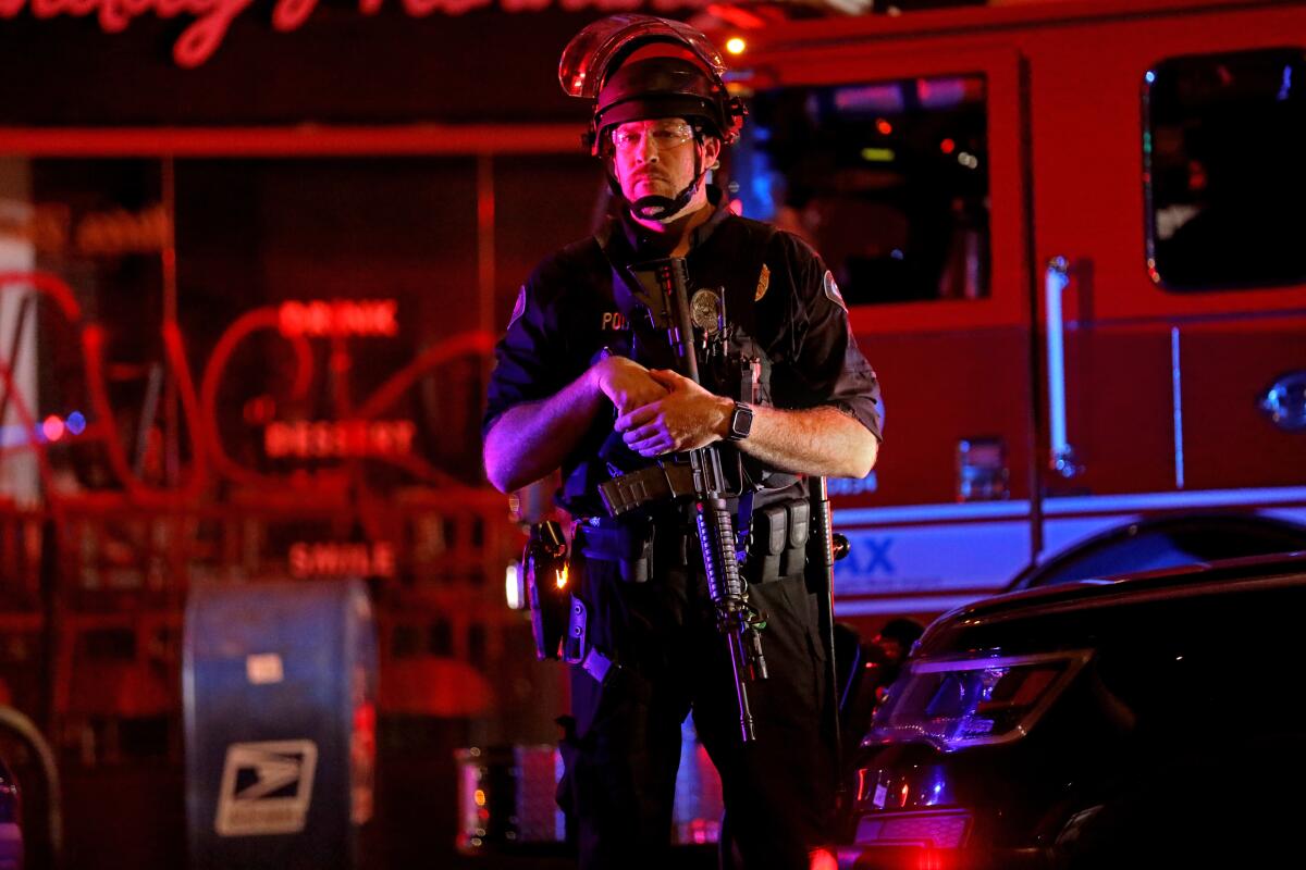 A Los Angeles police officer stands guard near ransacked businesses in the Melrose district on May 30.