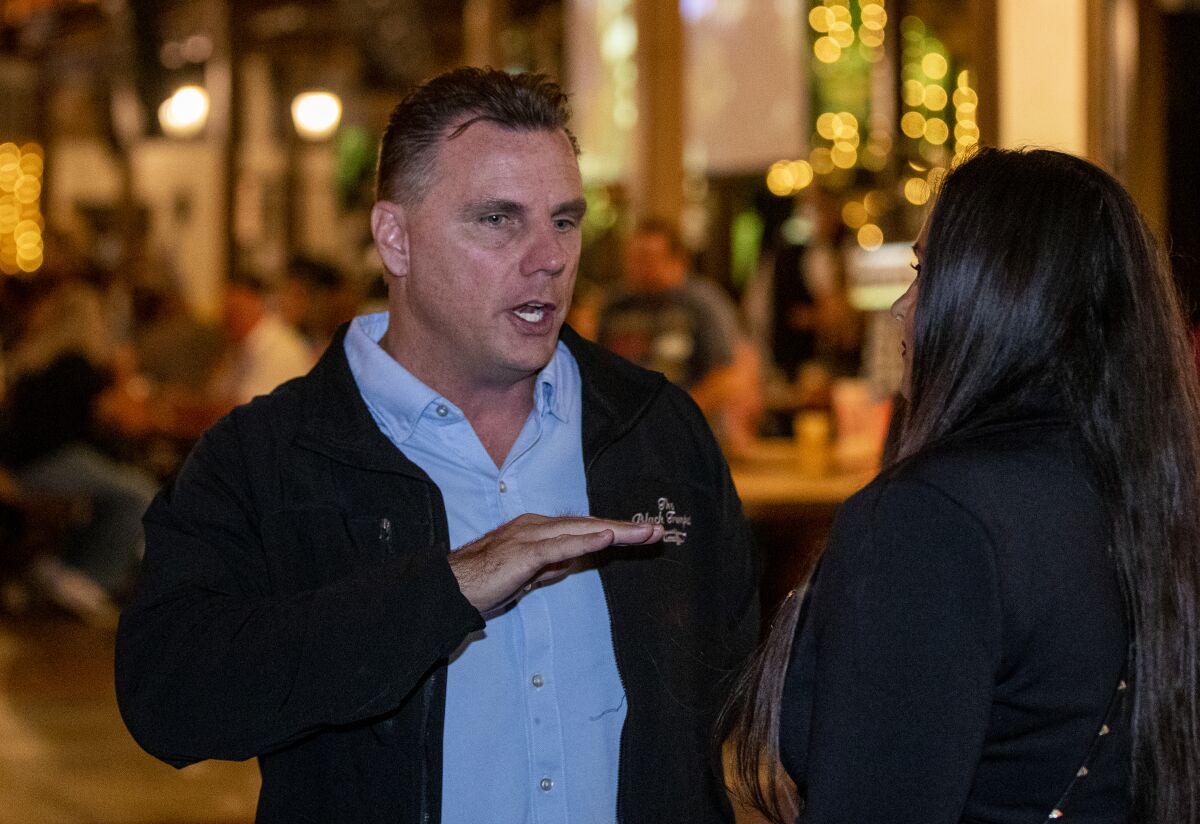 Huntington Beach City Attorney Michael Gates, left, speaks with a City Council candidate in Huntington Beach on Oct. 2.