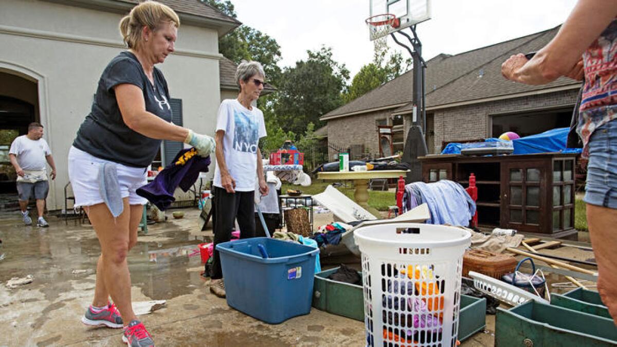 Family and friends help Sheila Siener, center, clean out her flood-damaged home Saturday in St. Amant, La.