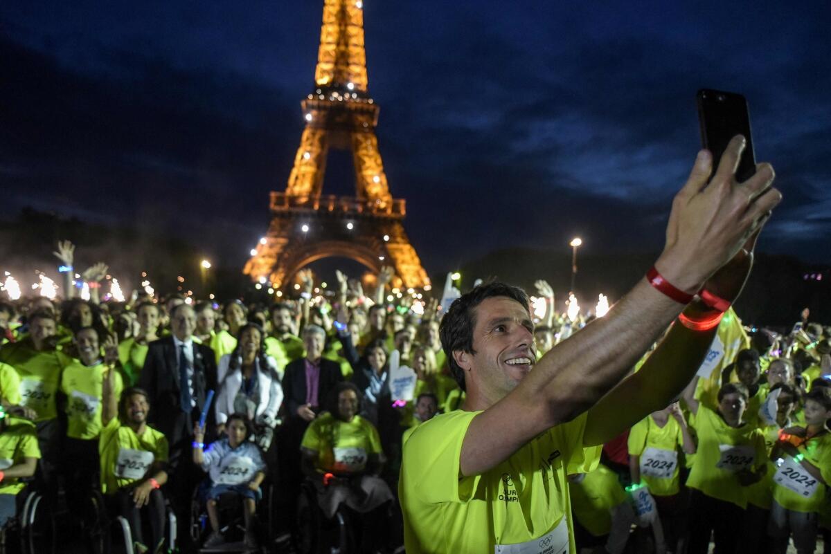 French slalom canoeist Tony Estanguet takes a selfie with the crowd in front of the Eiffel tower after finishing "2024 meters run" during the "Olympics Day" organized by the city of Paris and the "Comite National Olympique et Sportif Francais " (CNOSF) to celebrate the upcoming of the 2024 Paris Olympics Games, in Paris on June 23, 2018.
