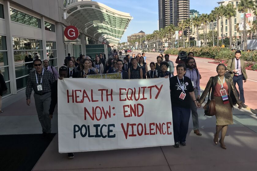Attendees at a public health meeting protest police violence