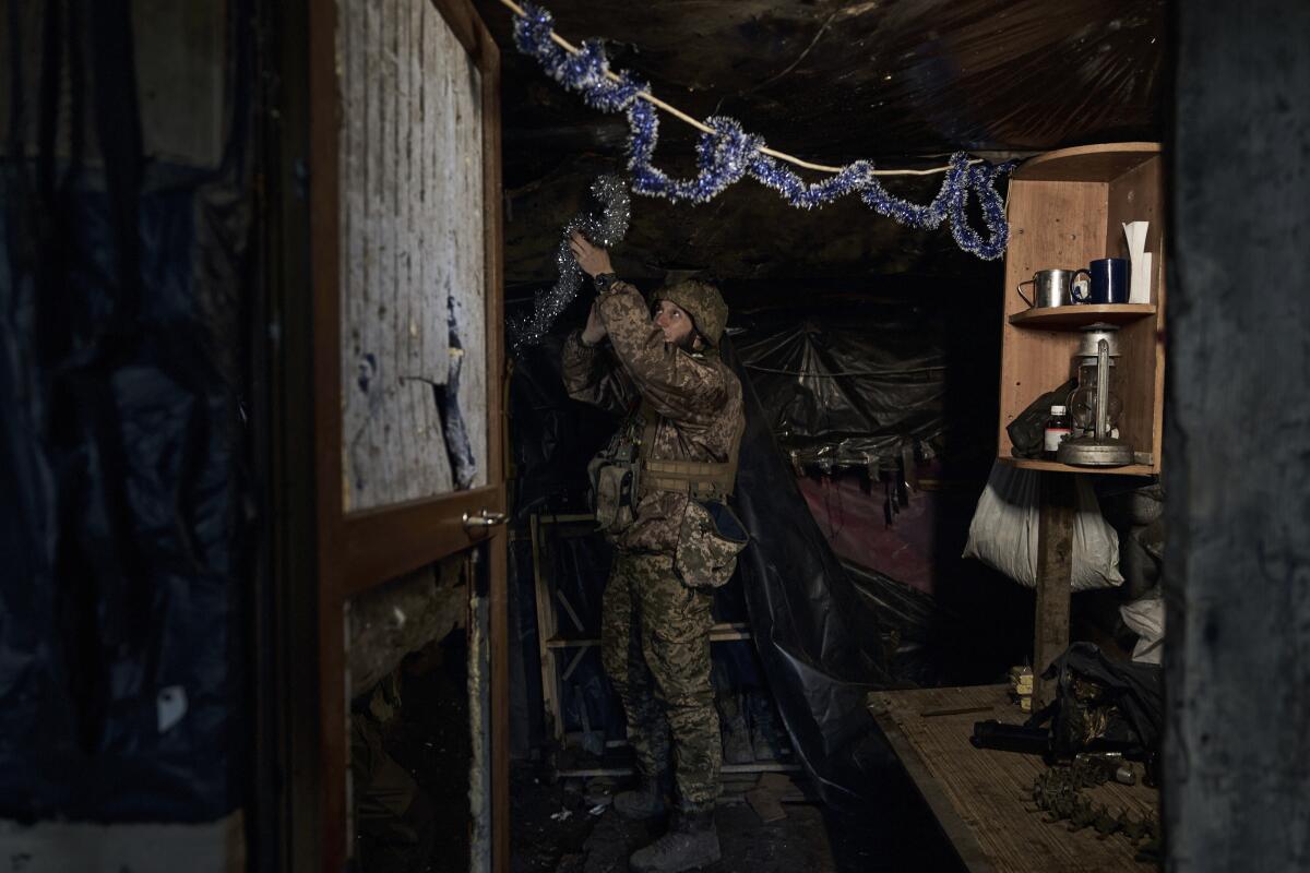 A Ukrainian soldier decorates a a home with tinsel.