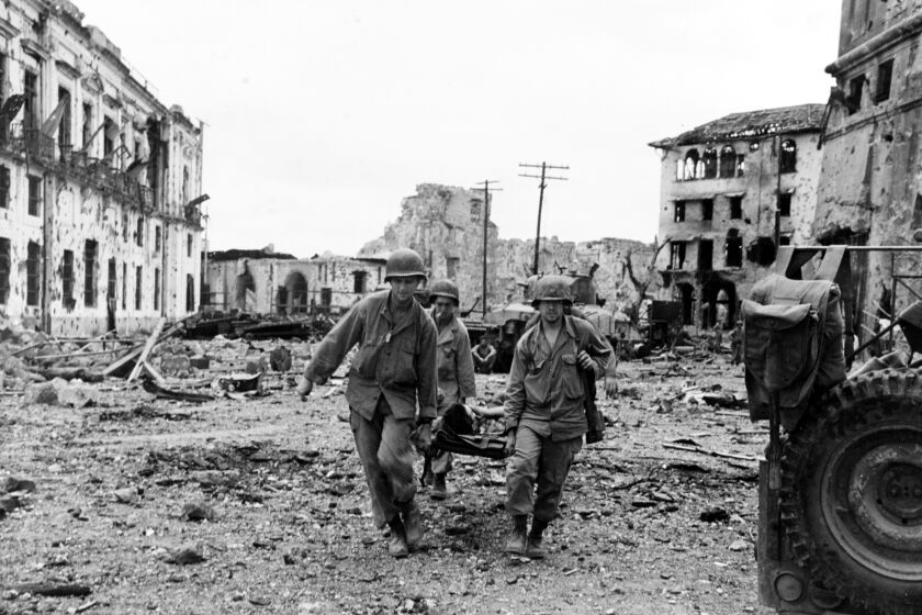 Liberation of Manila, 1945. Stretcher party brings out a wounded U.S. soldier, following an attack by U.S. troops to liberate Filipino prisoners in the walled city, 23 February 1945. Note wrecked buildings.
