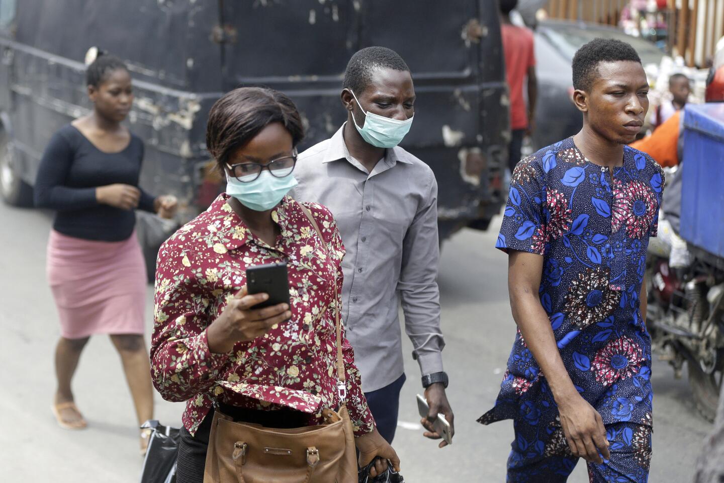 Nigeria: People wearing face masks walk through a busy market in Lagos, Nigeria.
