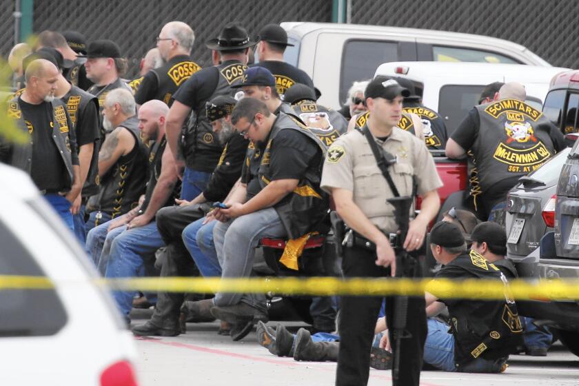 A McLennan County deputy stands guard near a group of bikers outside a restaurant in Waco, Texas, on May 17 after a shootout that involved two motorcycle gangs.