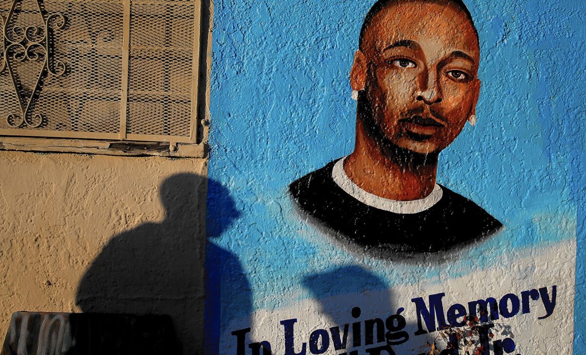 Passersby pause at a memorial to Ezell Ford, a mentally ill black man killed by police in South L.A. last year. The Los Angeles Police Department and its inspector general have said the shooting was justified, according to sources.