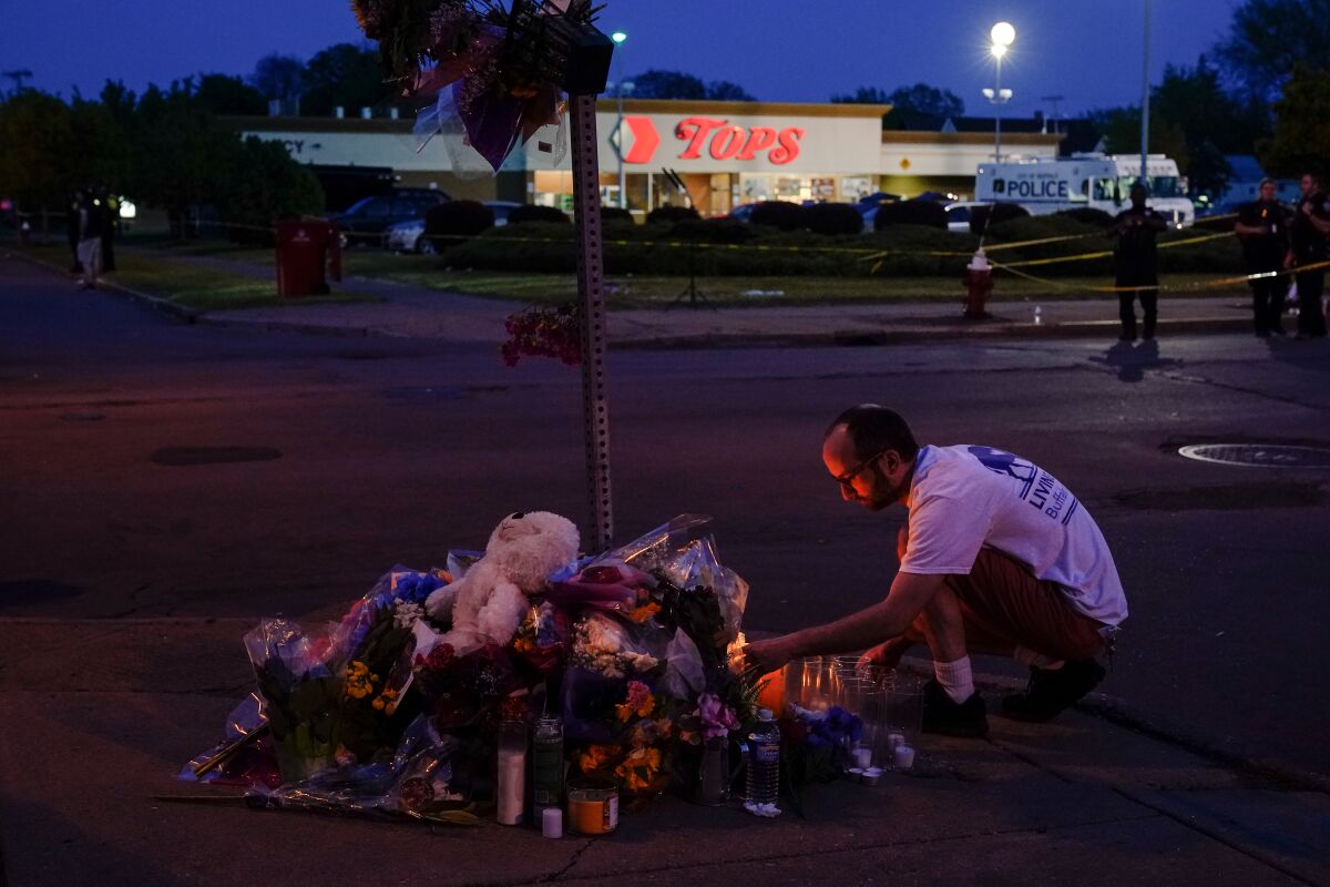 A man kneels at a makeshift memorial outside a Tops store in Buffalo.