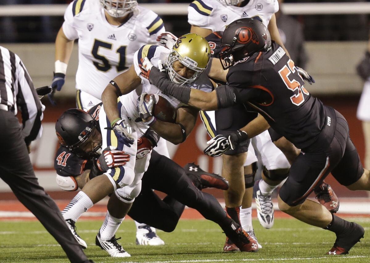 UCLA running back Jordon James carries the ball as Utah linebackers Jared Norris (41) and Jason Whittingham make a tackle in the second quarter during the Bruins' 34-27 victory Thursday night.