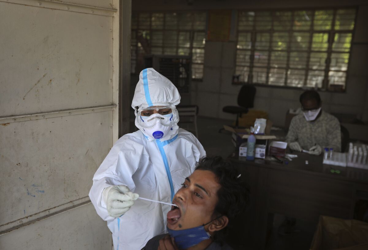 A heath worker takes nasal samples to test for COVID-19 in New Delhi, India, Tuesday, Nov. 3, 2020. Even as India's overall coronavirus cases continue to fall, health officials say that New Delhi is in the grip of its third and worst wave of infections yet. (AP Photo/Manish Swarup)