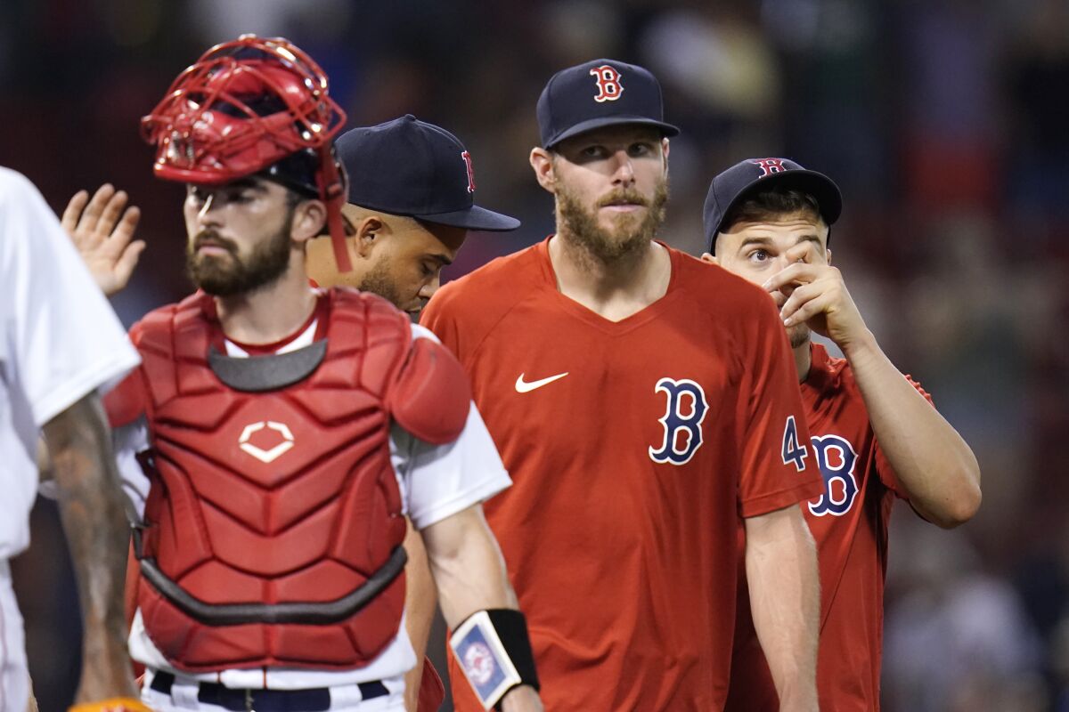 Boston Red Sox pitcher Chris Sale, center, who is on the disabled list, walks with teammates after a 20-8 win against the Tampa Bay Rays after a baseball game at Fenway Park, Wednesday, Aug. 11, 2021, in Boston. (AP Photo/Charles Krupa)