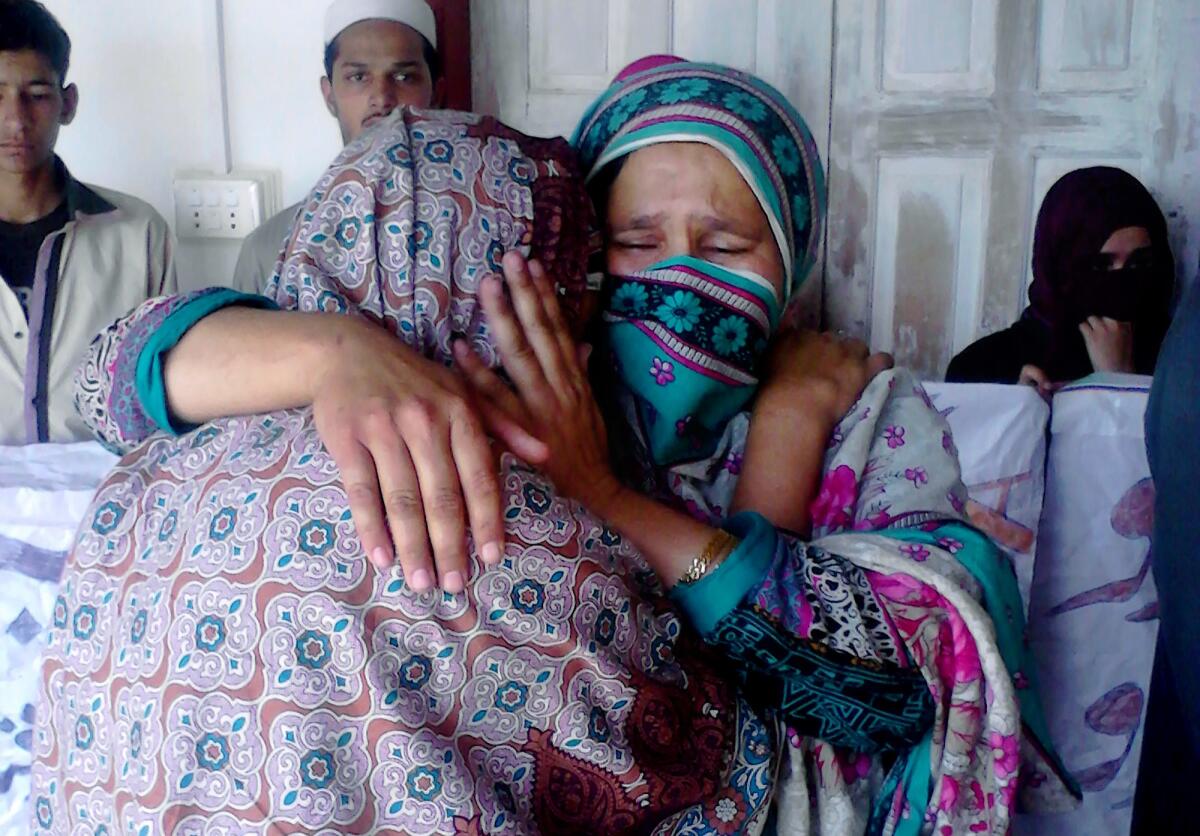 Relatives of a female teacher who was beaten and set on fire comfort each other in Upper Dewal, Pakistan.