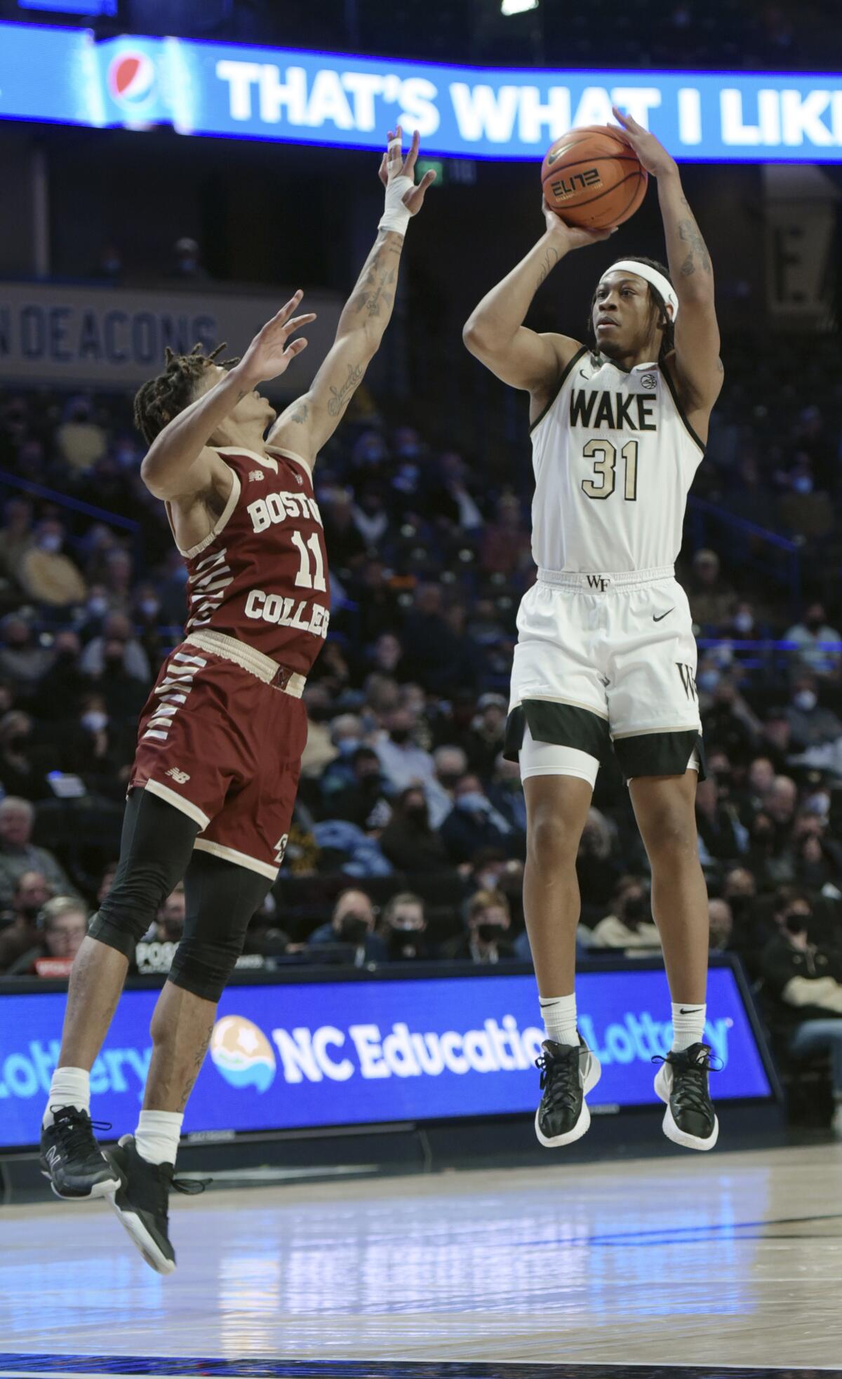 Wake Forest's Alondes Williams shoots from the top of the key under pressure from Boston College's Makai Ashton-Langford in the first half of an NCAA college basketball game, Monday, Jan. 24, 2022, in Winston-Salem, N.C. (Walt Unks/The Winston-Salem Journal via AP)