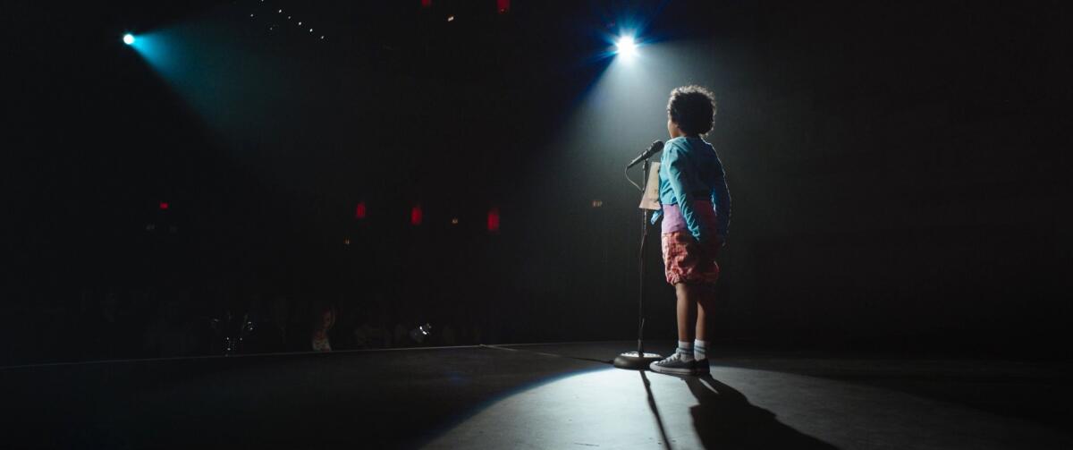 A child stands onstage before a microphone in a scene from the film "Definition Please"