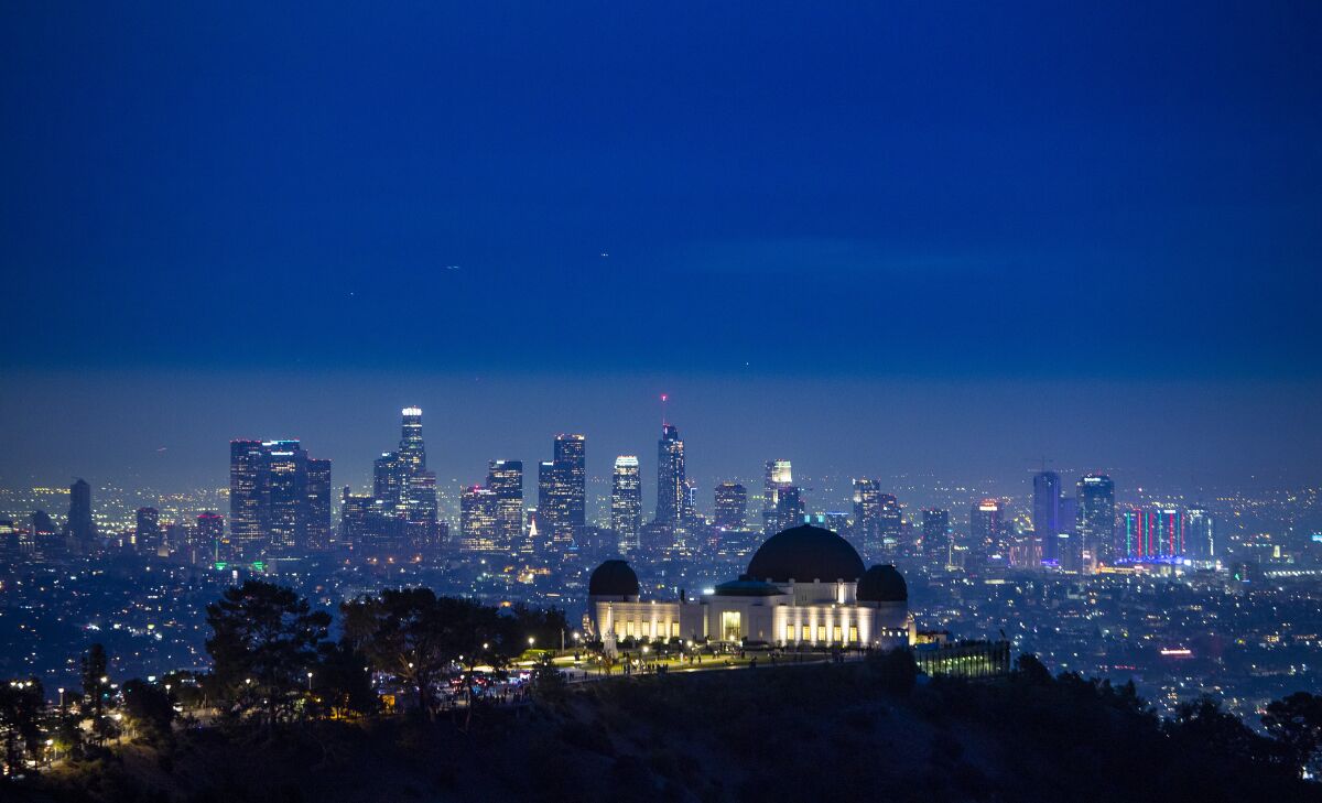 The Los Angeles skyline after dark with a lighted observatory in the foreground.