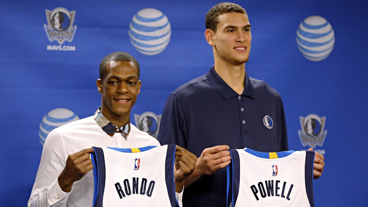 Rajon Rondo, left, and Dwight Powell hold their new Dallas Mavericks jerseys during a news conference Friday.