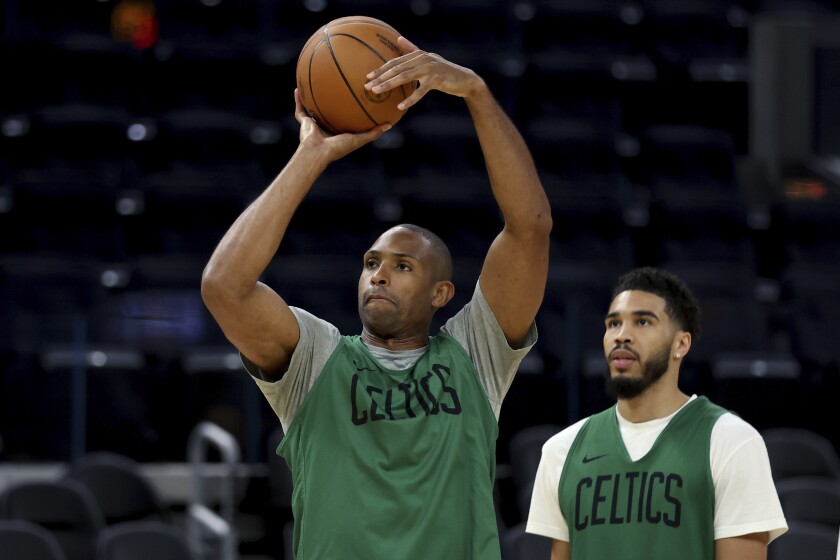Boston Celtics' Al Horford shoots as Jayson Tatum watches practice.