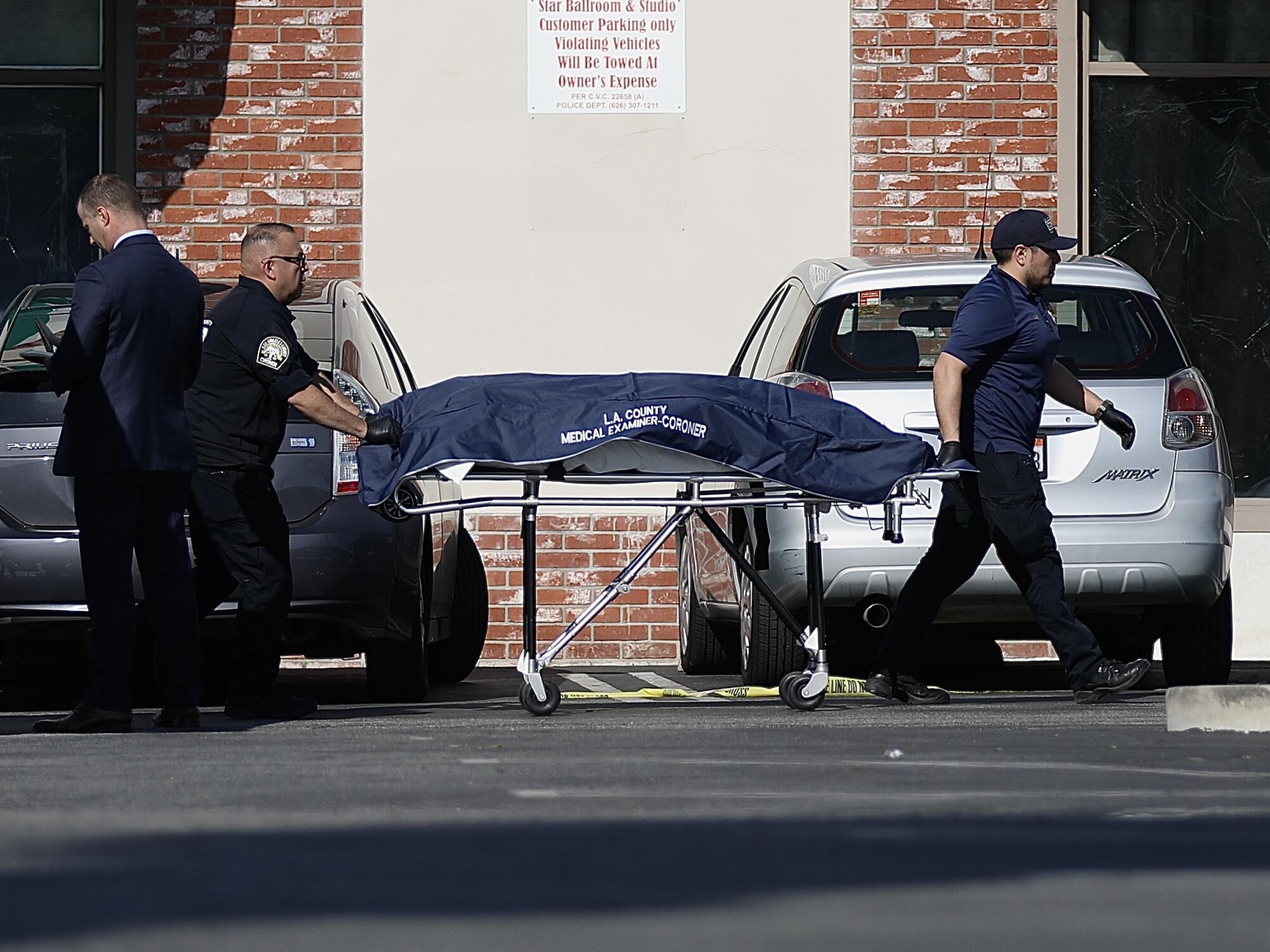 Los Angeles County coroners remove the body of one of the victims from the rear parking lot.