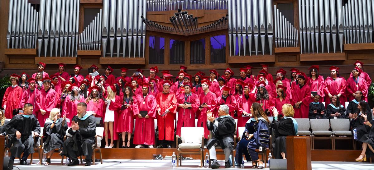 School and district administrators, front, cheer Back Bay High School's graduating class of 2025 in a ceremony Thursday.