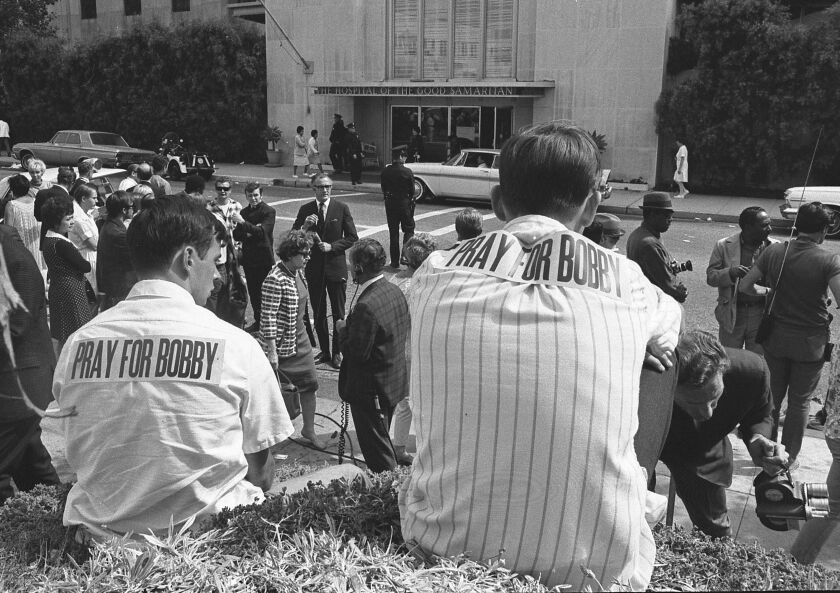 People, including two brothers wearing "Pray for Bobby" stickers on their backs in Los Angeles in 1968.