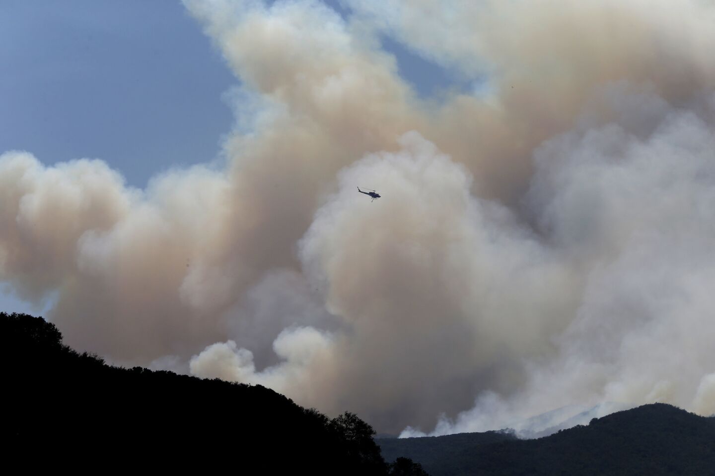 A firefighting helicopter gets into position to make a water drop on the Whittier fire as it burns toward State Route 154 in the Los Padres National Forest near Lake Cachuma.