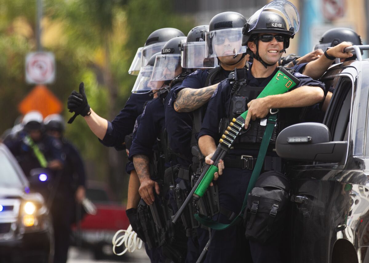 A group of police officers stand alongside a vehicle