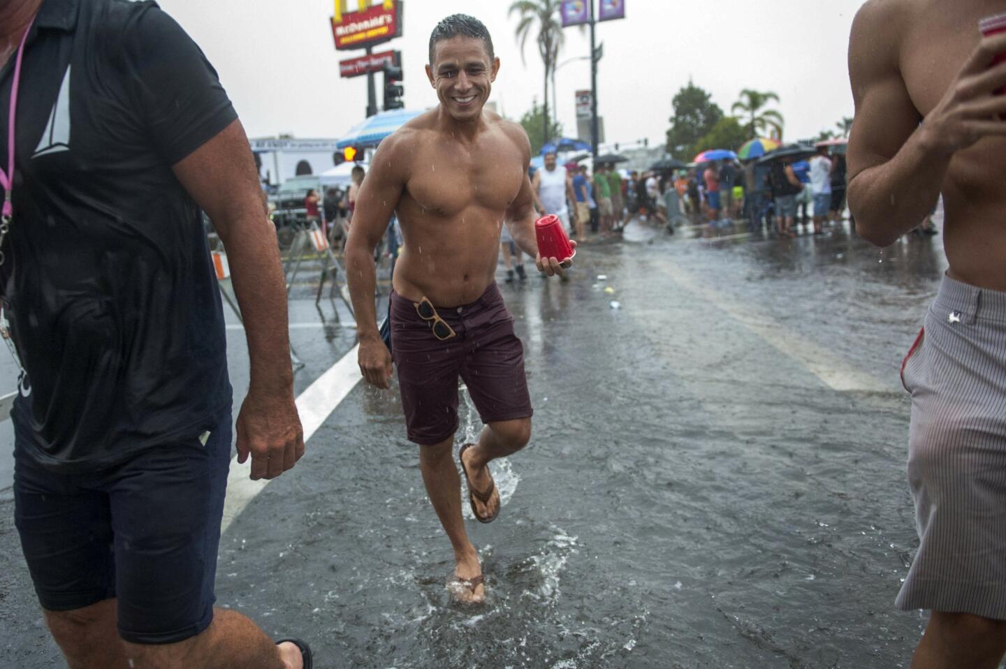 Jeff Ali wades through a large puddle of water on Richmond Street while attending the San Diego Pride Parade.