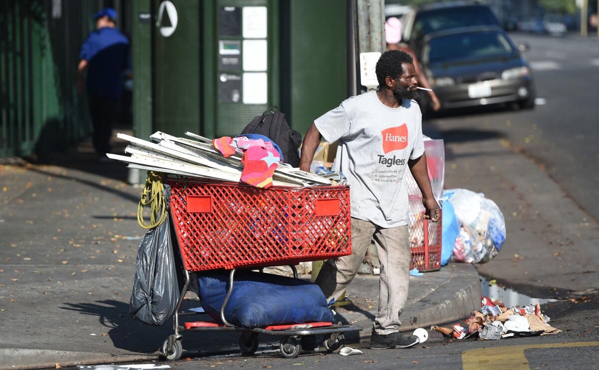 A homeless man pushes his belongings in a shopping cart on skid row, which has one of the largest populations of homeless people in the United States.