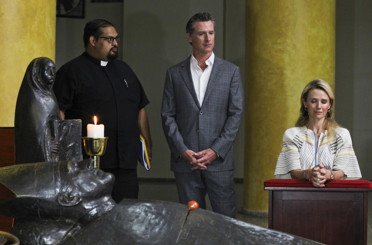 Gov. Gavin Newsom and wife Jennifer Siebel Newsom, visit the tomb of Archbishop Oscar Romero at Metropolitan Cathedral in San Salvador, El Salvador with Father Francisco Villalobos, left. Romero was assassinated in 1980 because he advocated for human rights and the poor.