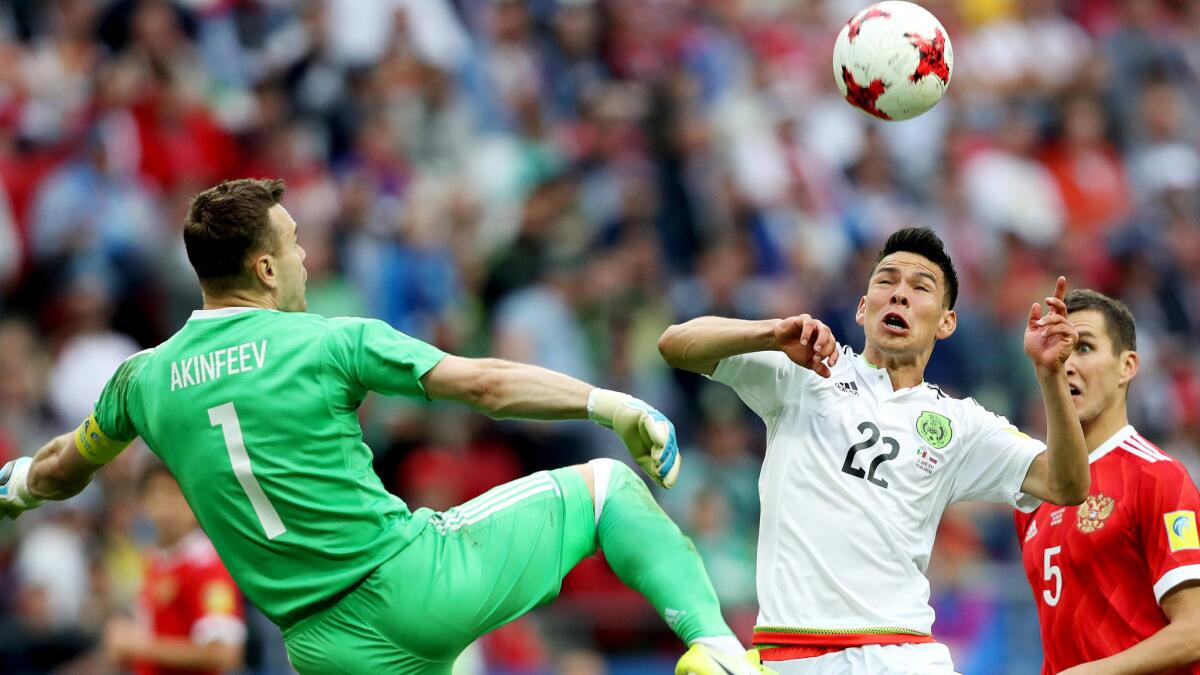 Mexico's Hirving Lozano heads the ball over Russia goalkeeper Igor Akinfeev for a goal Saturday.