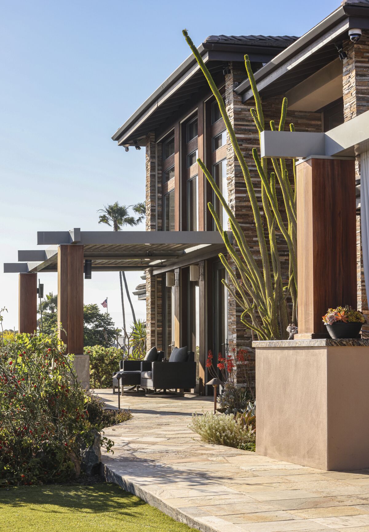 An outdoor seating area under a pergola of a multistory home.