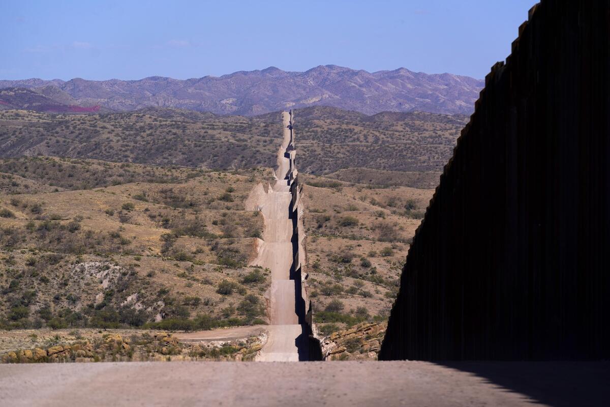 FILE - In this May 19, 2021 file photo the border wall stretches along the landscape near Sasabe, Ariz. The bodies of an unusually large number of migrants who died in Arizona's borderlands are being recovered this summer amid record temperatures that are regularly soaring above 110 degrees in the state's sun scorched desert and rugged mountains. (AP Photo/Ross D. Franklin,File)