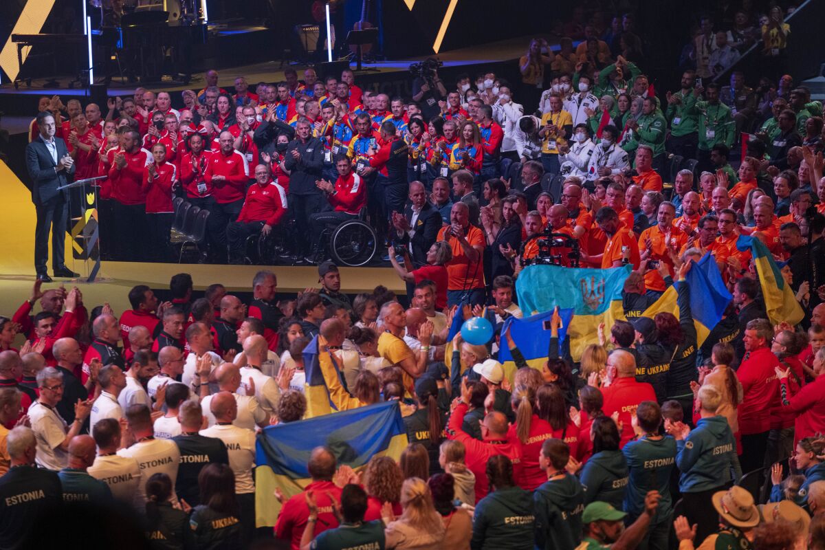 Dutch Prime Minister Mark Rutte, left, athletes and the audience gave a long standing ovation to the team from Ukraine, center with blue and yellow flags, during the opening ceremony of the Invictus Games venue in The Hague, Netherlands, Saturday, April 16, 2022. The week-long games for active servicemen and veterans who are ill, injured or wounded opens Saturday in this Dutch city that calls itself the global center of peace and justice. (AP Photo/Peter Dejong)