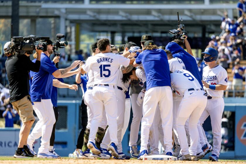 LOS ANGELES, CA - MAY19, 2024: Los Angeles Dodgers designated hitter Shohei Ohtani (17) is swarmed by teammates after hitting his first walk-off hit as a Dodger to beat the Cincinnati Reds 3-2 in 10 innings at Dodger Stadium on May 19, 2024 in Los Angeles, California.(Gina Ferazzi / Los Angeles Times)