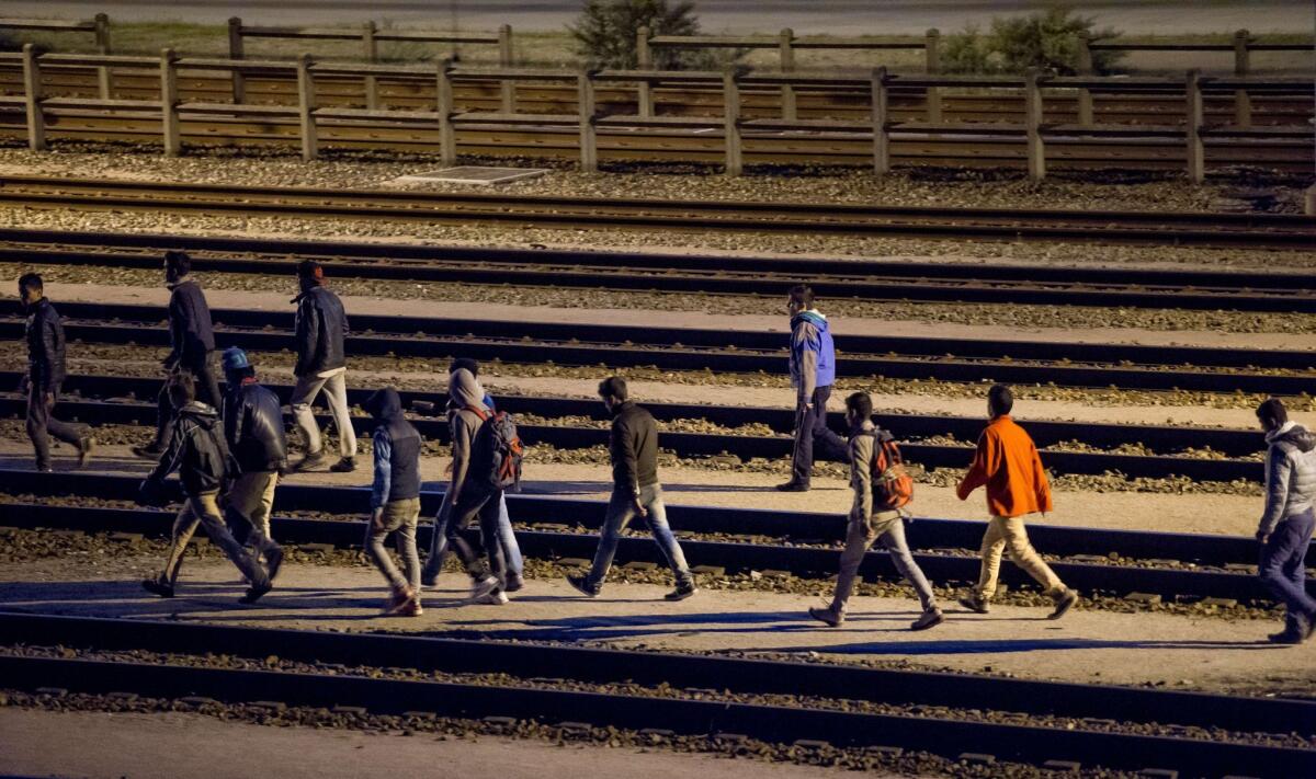 Migrants walk along railway tracks at the Eurotunnel terminal July 28 in Calais-Frethun, France.