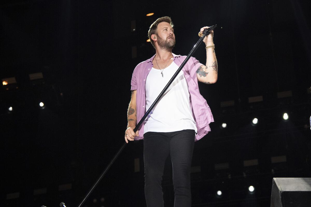 Charles Kelley of Lady A holds a microphone and stand while performing on stage