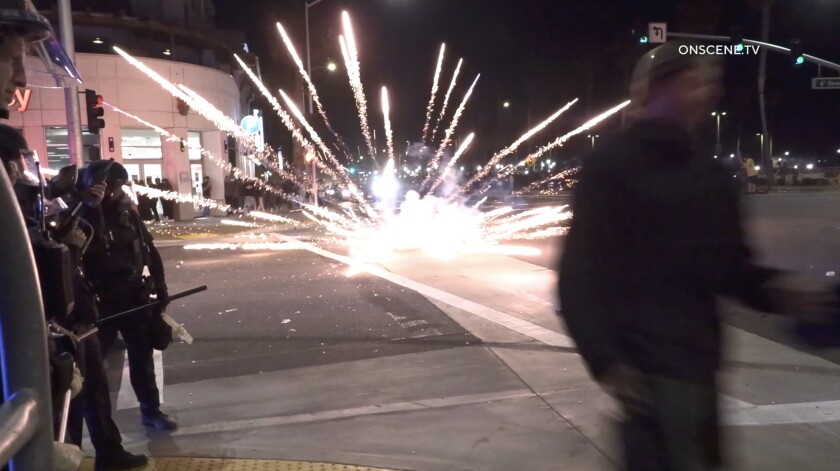 Fireworks explode among people on a street.