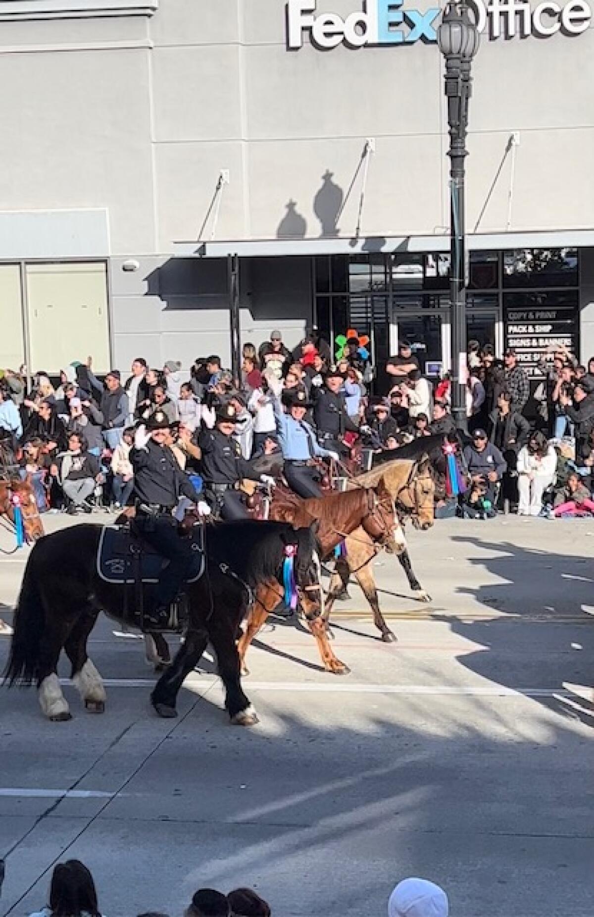 Mounted officers from the Newport Beach Police Department wave to Rose Parade crowd.