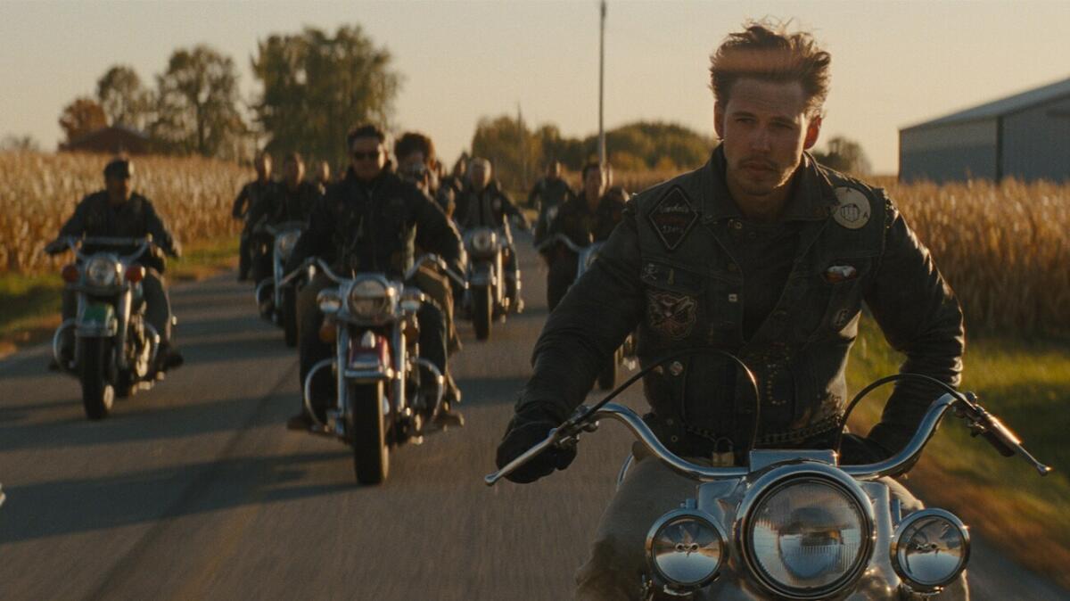 A motorcycle gang heads down the road at dusk.