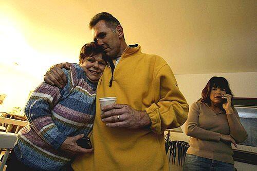 June Linn is hugged by her son in law, California Highway Patrol officer Edward Smith as they watch news of her son's rescue.