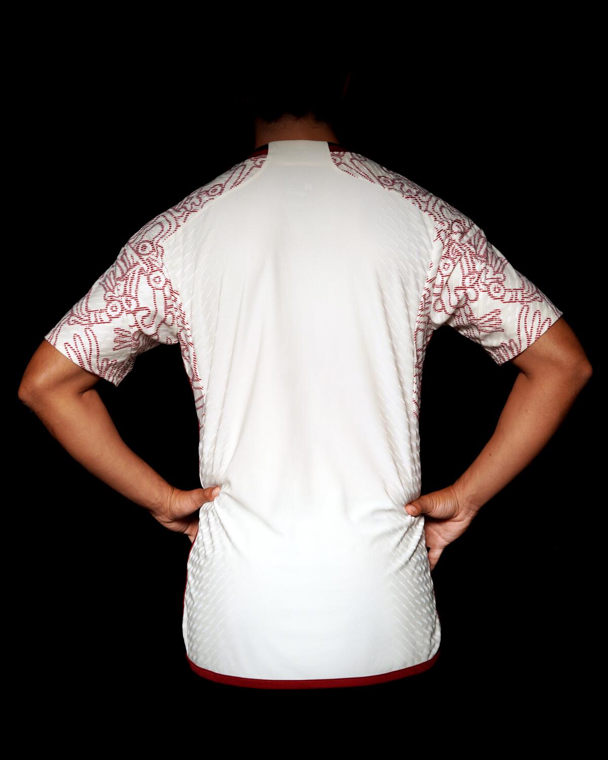 The white back of a shirt with red outlined designs on the front and short sleeves