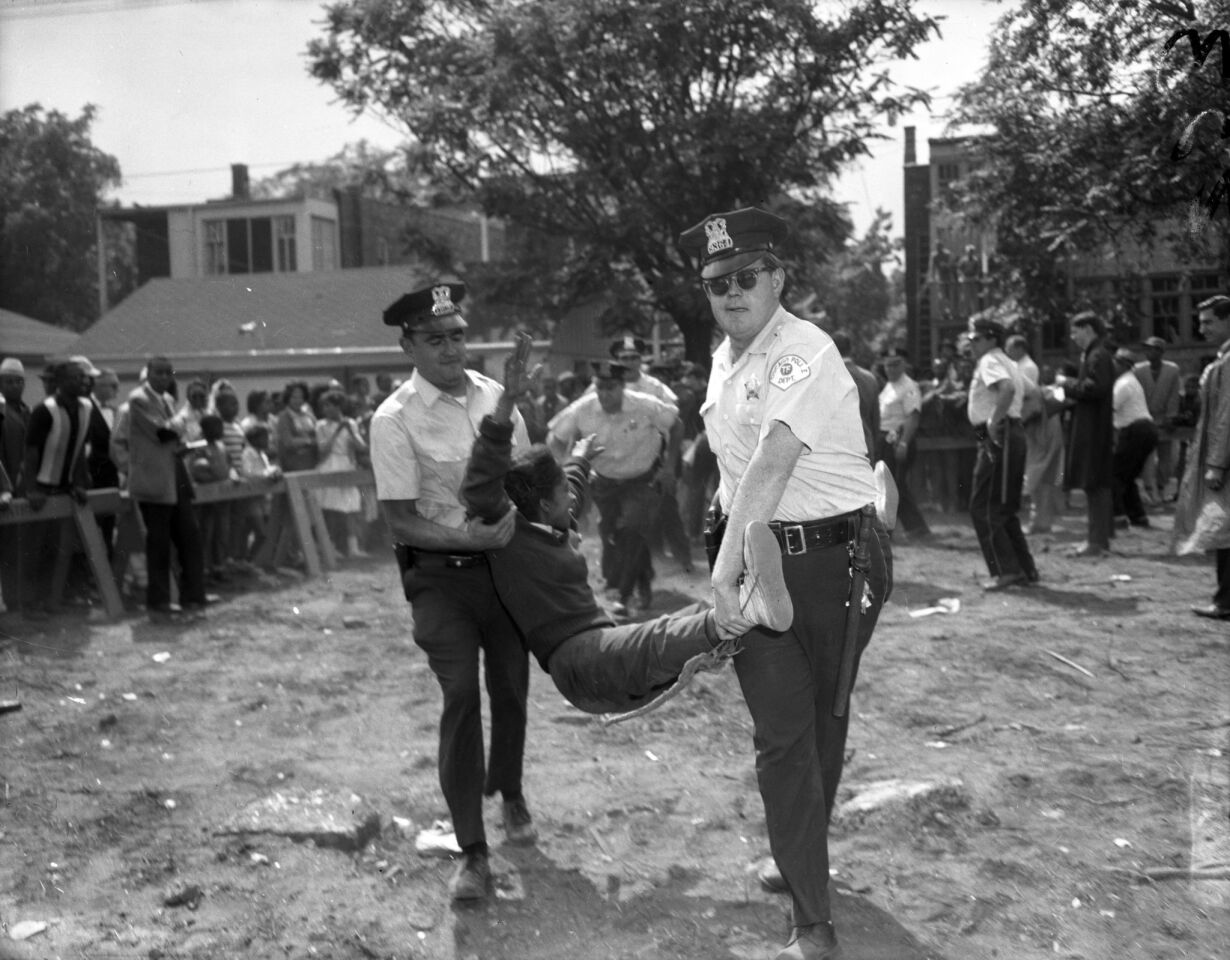 Chicago police officers carry a protester to a police wagon from the mobile classroom site at 73rd Street and Lowe Avenue in Chicago's Englewood neighborhood Aug. 13, 1963.